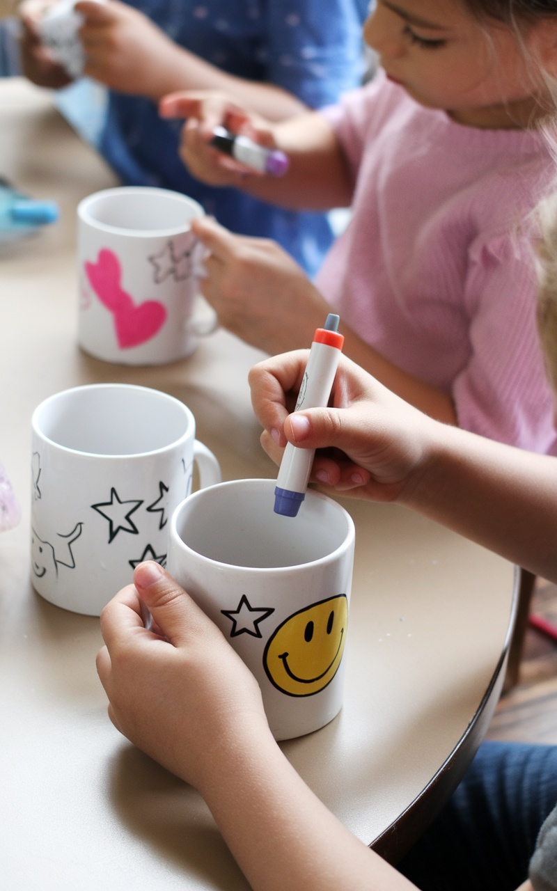 Children holding customized mugs with colorful designs